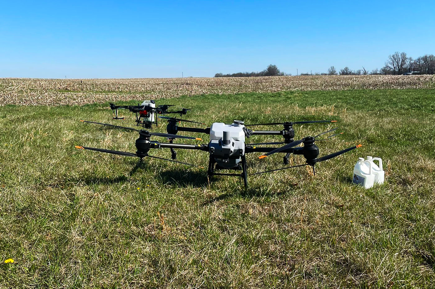 two drones in field with white plastic bottles